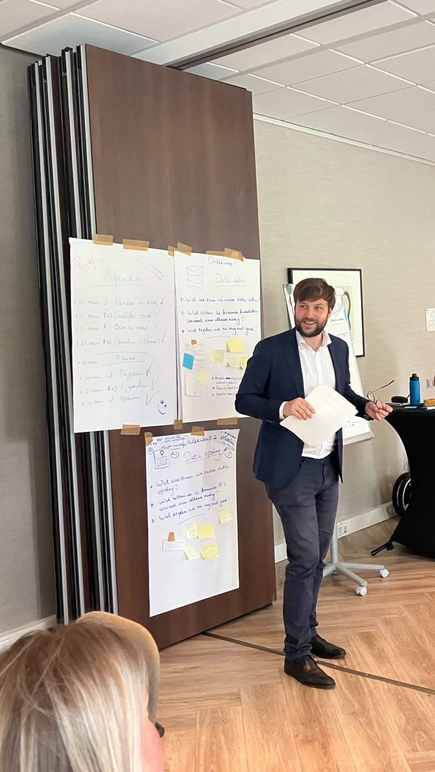 Damian facilitating a workshop beside flip charts showing the session agenda